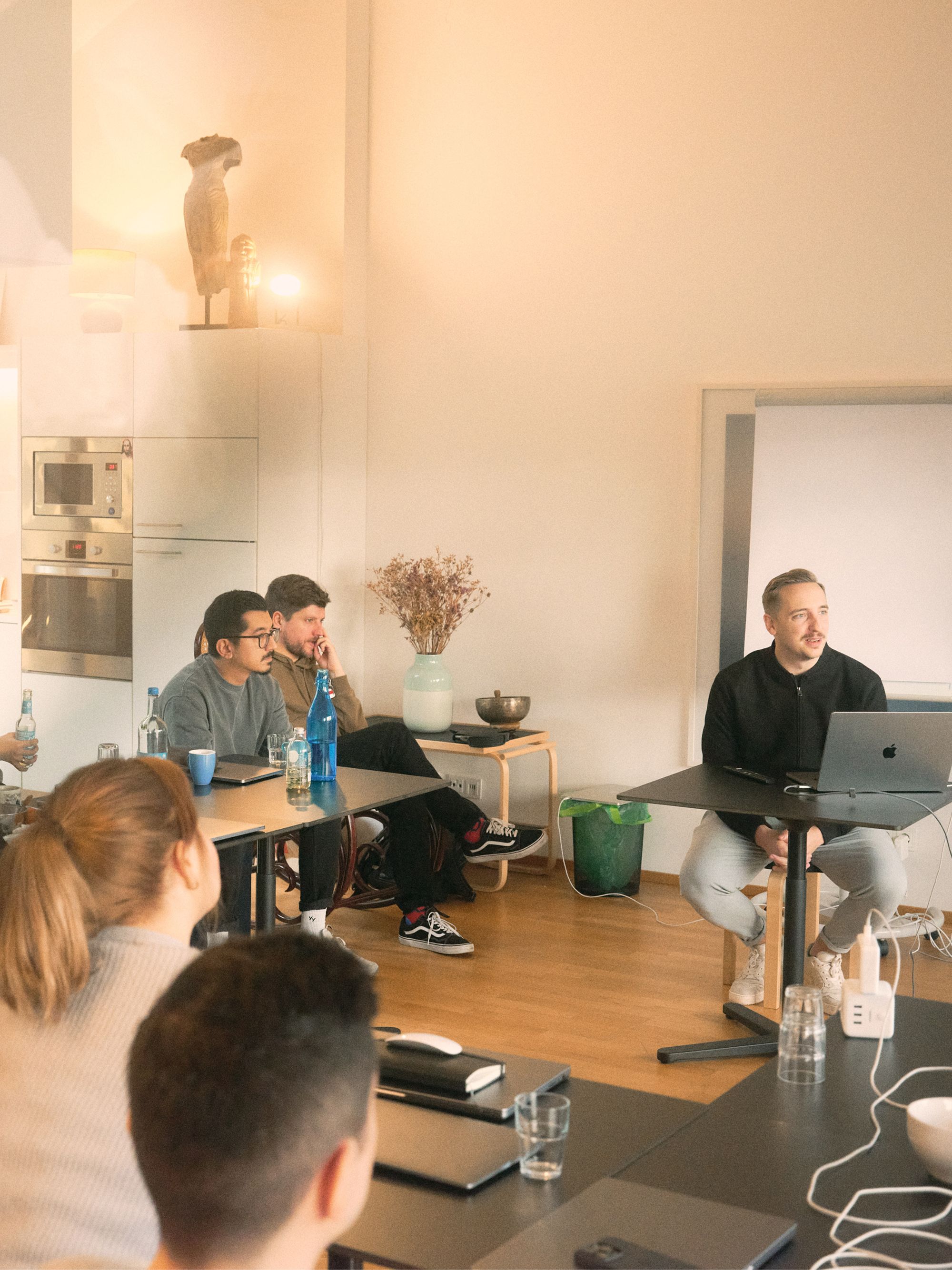 Group of people attending a meeting or presentation in a room with a presenter using a laptop